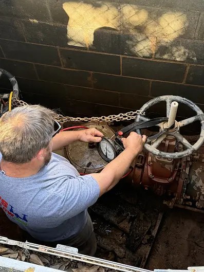 Technician working on a backflow assembly inside a below grade commercial valve vault